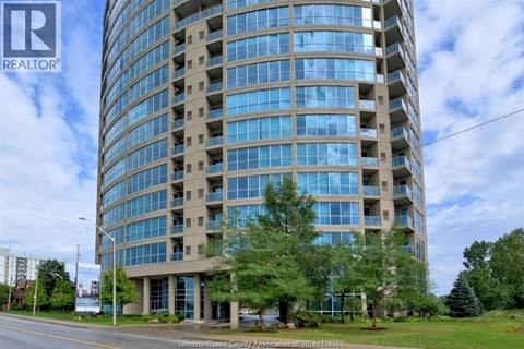 A tall building with many windows is surrounded by trees and grass.