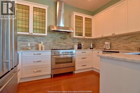 A kitchen with white cabinets and a stainless steel refrigerator.