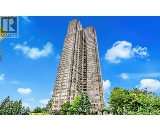 A tall building with a glass facade stands in front of a blue sky with clouds.