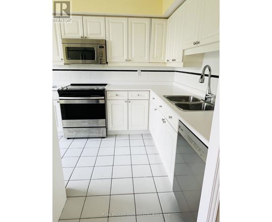 A white kitchen with a black oven and a white tiled floor.