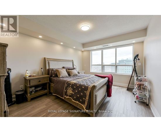 A bedroom with a large bed and a window overlooking the city.