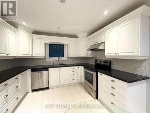 A kitchen with white cabinets and black countertops.