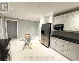 A kitchen with white cabinets and black countertops.
