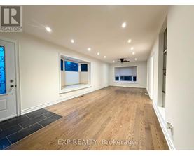 A spacious room with wooden flooring and a ceiling fan.