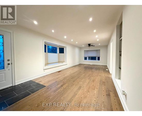 A spacious room with wooden flooring and a ceiling fan.