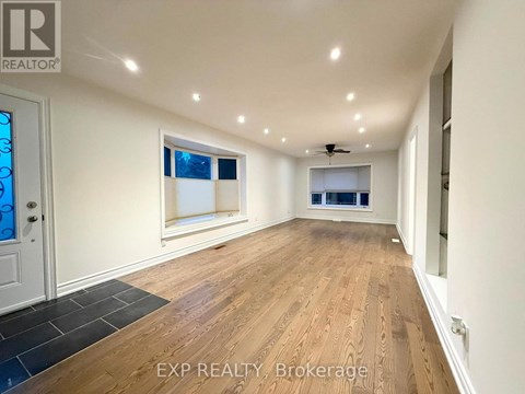 A spacious room with wooden flooring and a ceiling fan.