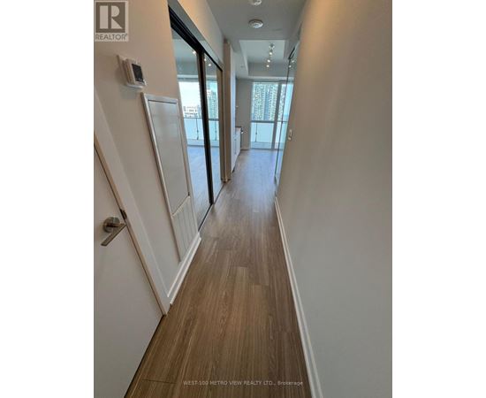 A hallway with wood flooring and white walls.