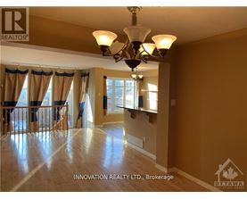 A well-lit, spacious room with a chandelier and hardwood floors.