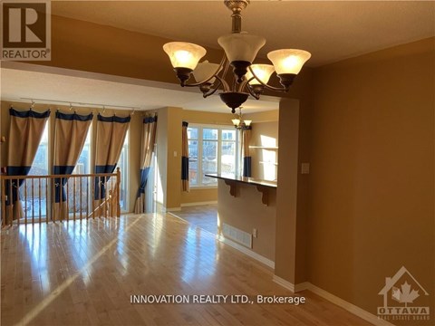 A well-lit, spacious room with a chandelier and hardwood floors.