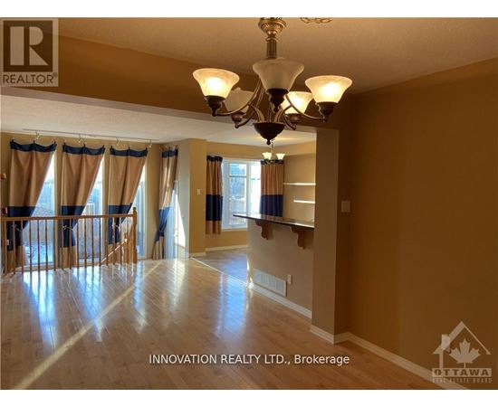 A well-lit, spacious room with a chandelier and hardwood floors.