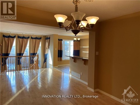 A well-lit, spacious room with a chandelier and hardwood floors.