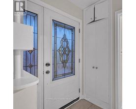 A white door with a stained glass window and a white cabinet to the right.
