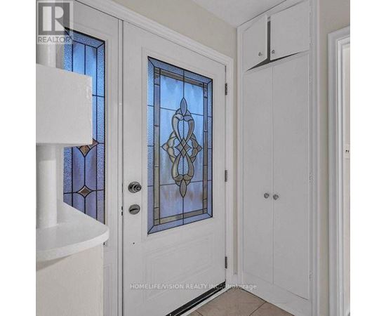 A white door with a stained glass window and a white cabinet to the right.