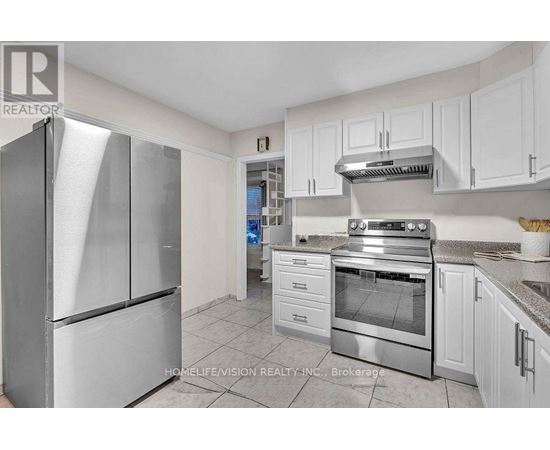 A kitchen with a refrigerator, oven, and cabinets.