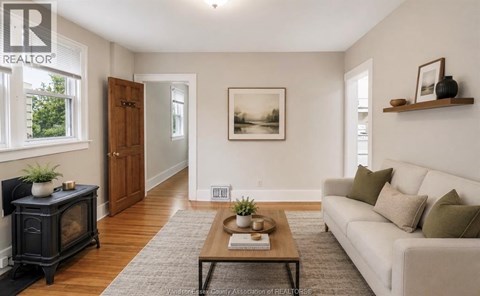 A living room with a white couch, a black fireplace, and a painting on the wall.