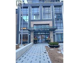 A modern building with a glass entrance and a stone walkway leading to it.
