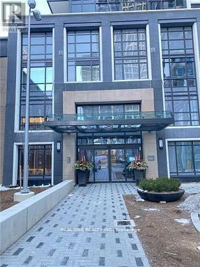 A modern building with a glass entrance and a stone walkway leading to it.