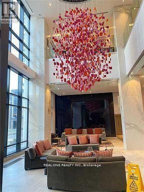 A large chandelier with red and white decorations hangs from the ceiling in a spacious room.