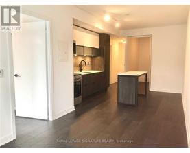 A modern kitchen with dark wood floors and white walls.