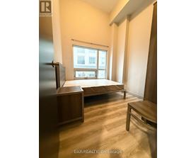 A bedroom with a bed, a table, and a refrigerator.