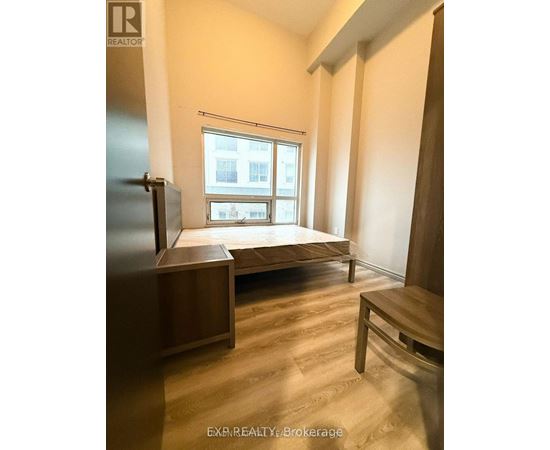 A bedroom with a bed, a table, and a refrigerator.