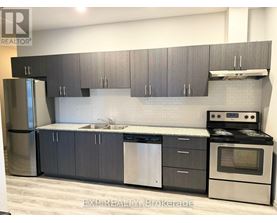 A modern kitchen with dark grey cabinets and stainless steel appliances.