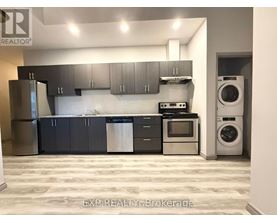 A kitchen with a refrigerator, oven, and washing machine.