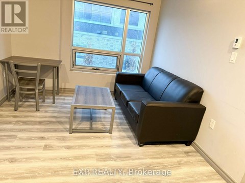 A living room with a black leather couch, a wooden coffee table, and a dining table with chairs.