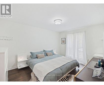 A bedroom with a bed, nightstand, and a window with white curtains.