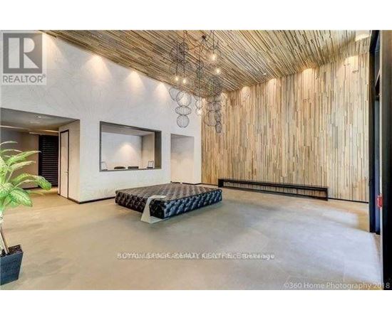 A bedroom with a bed, a plant, and a wooden wall.