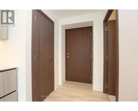 A hallway with two doors and a brokerage sign.