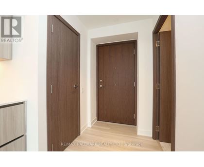 A hallway with two doors and a brokerage sign.