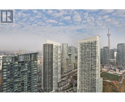 A cityscape with tall buildings and a tower in the distance.