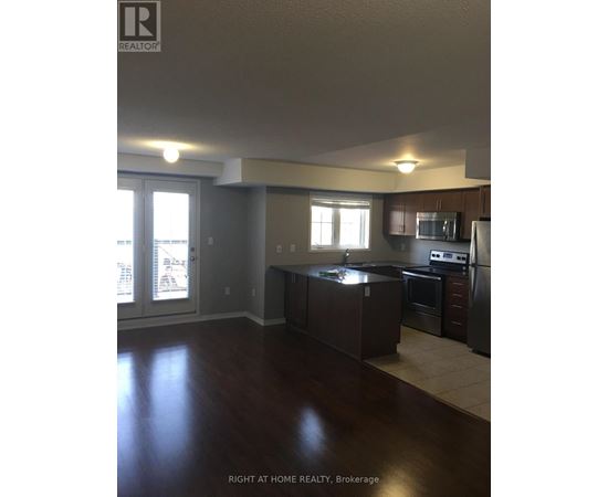 A kitchen with dark wood floors and stainless steel appliances.