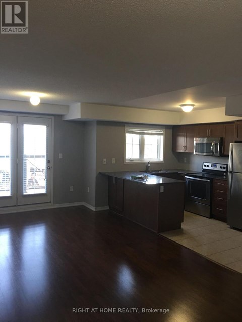 A kitchen with dark wood floors and stainless steel appliances.