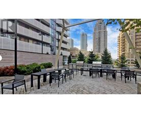 A patio area with black chairs and tables is set up in front of a building.