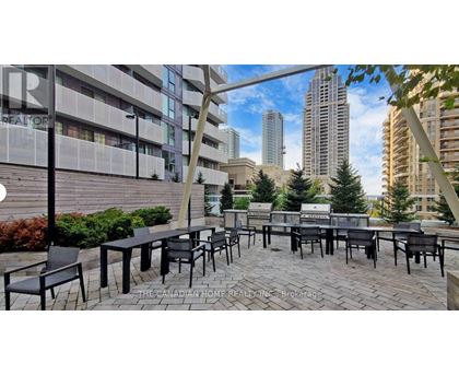 A patio area with black chairs and tables is set up in front of a building.