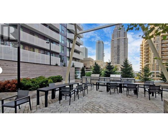 A patio area with black chairs and tables is set up in front of a building.
