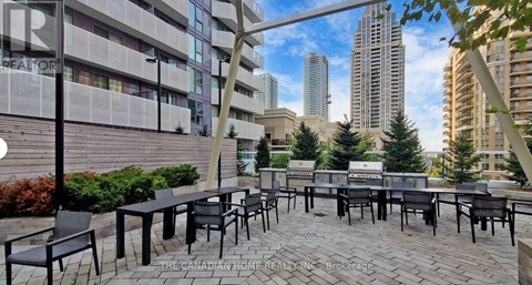 A patio area with black chairs and tables is set up in front of a building.