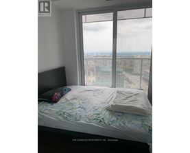 A bedroom with a large window overlooking a cityscape.