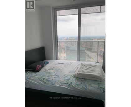 A bedroom with a large window overlooking a cityscape.