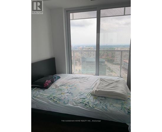 A bedroom with a large window overlooking a cityscape.