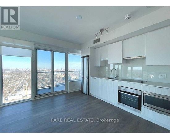 A spacious kitchen with white cabinets and a view of the city.