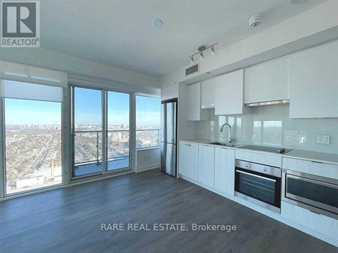 A spacious kitchen with white cabinets and a view of the city.