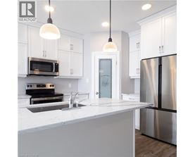 A modern kitchen with white cabinets and a stainless steel refrigerator.