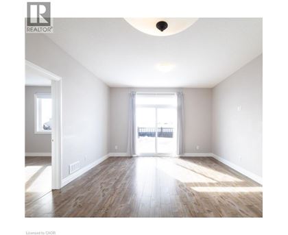 A spacious room with wooden flooring and a large window.