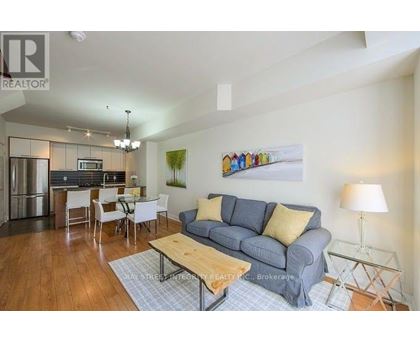 A living room with a grey couch and a painting on the wall.