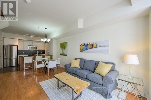 A living room with a grey couch and a painting on the wall.
