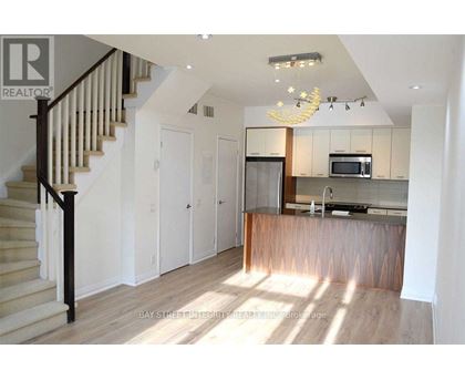 A well-lit kitchen with a bar counter and a staircase with wooden steps.