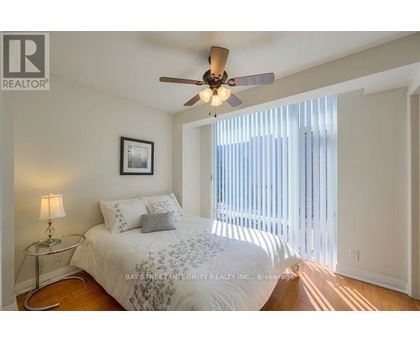 A bedroom with a bed, a ceiling fan, and a window with blinds.